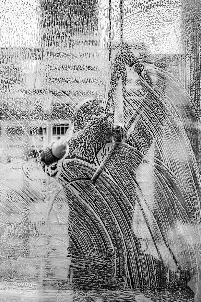 Monochromatic image capturing workers cleaning a window in Buenos Aires.